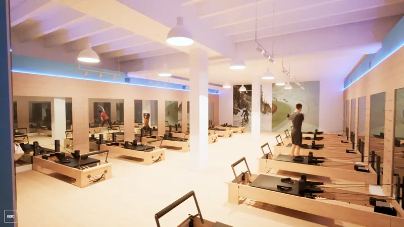 Midtown studio — rows of reformers beneath pendant lights and a white beamed ceiling.