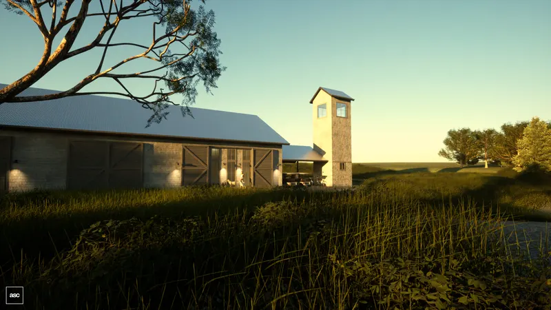 Long shed and square tower beyond a meadow and stone gateposts.