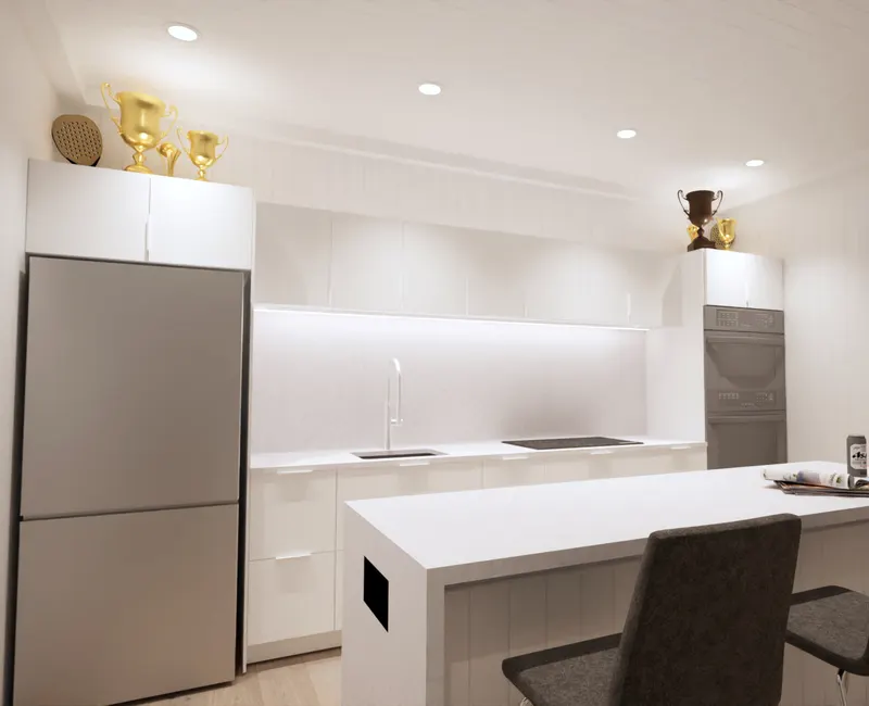 White clubhouse kitchenette with an island, dark stools and trophies above cabinetry.