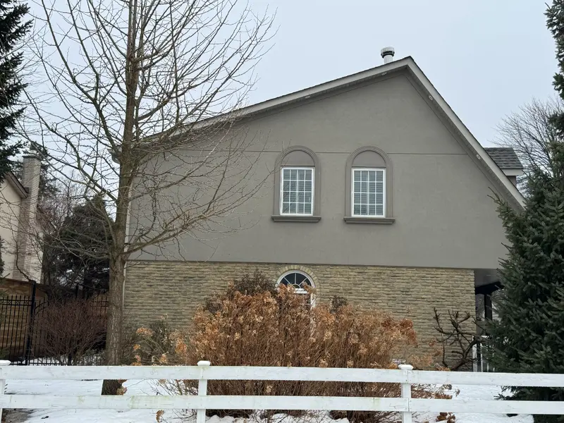 Existing side elevation with stucco and stone walls.