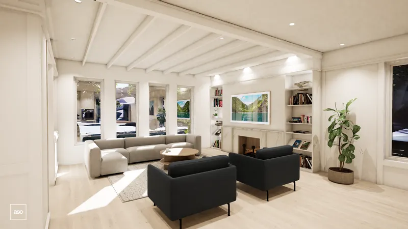 Bright living room with white ceiling beams, dark armchairs and a fireplace between bookshelves.