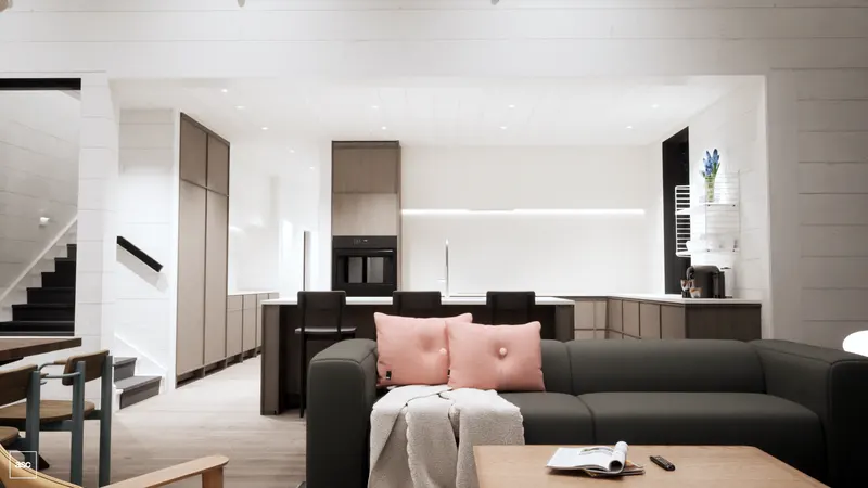 Timber kitchen cabinetry and a black island behind a grey sofa.
