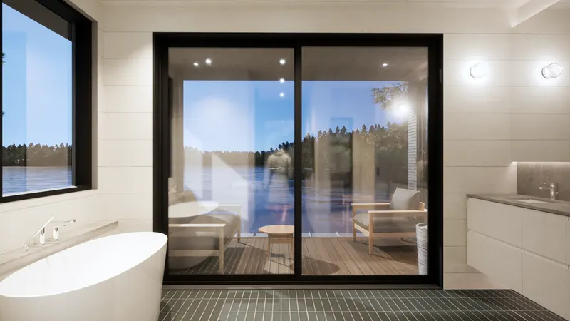 Freestanding bath beside glazed doors to a lakeside terrace.