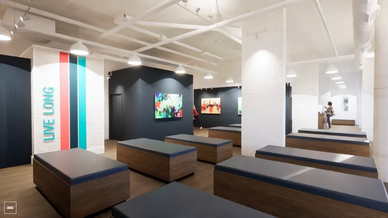 West studio — timber treatment benches beside a striped brand panel.